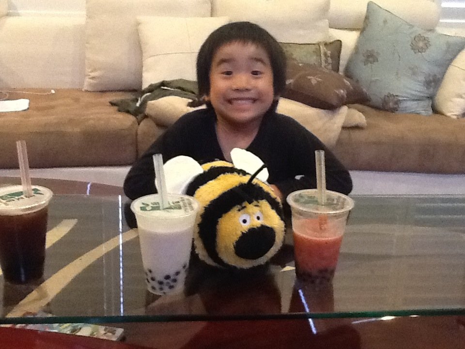 Aidan grinning behind a bumblebee plush and boba drinks