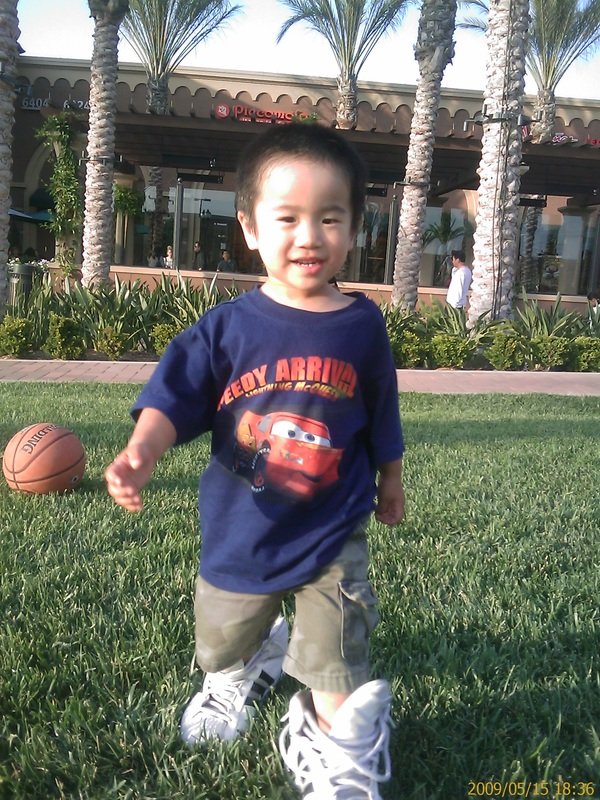 Aidan as a toddler chasing a basketball on the grass