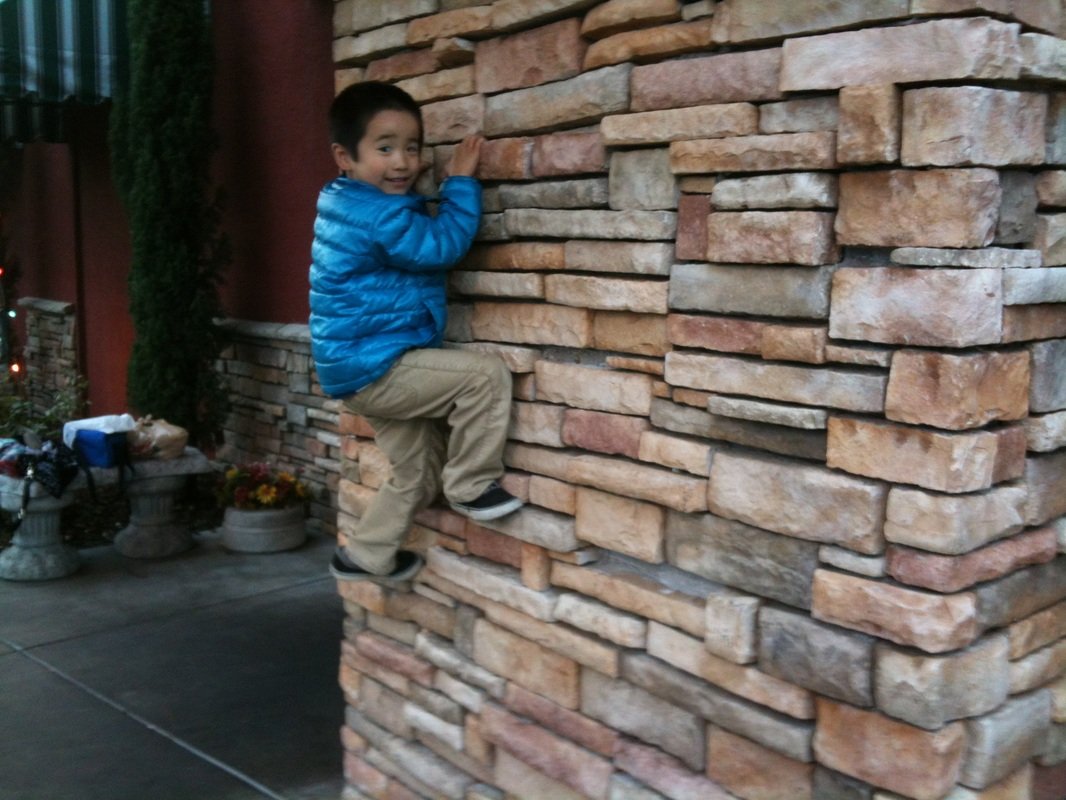 Aidan in a blue jacket climbing a stone wall