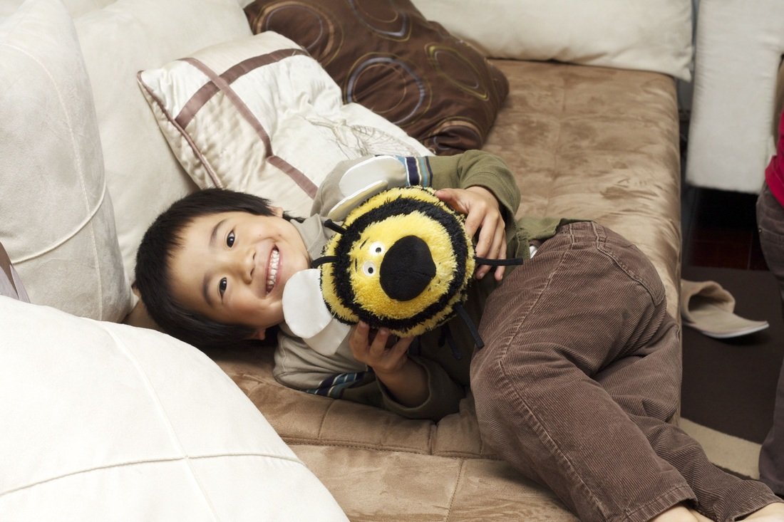 Aidan laughing on the couch with his bumblebee plush